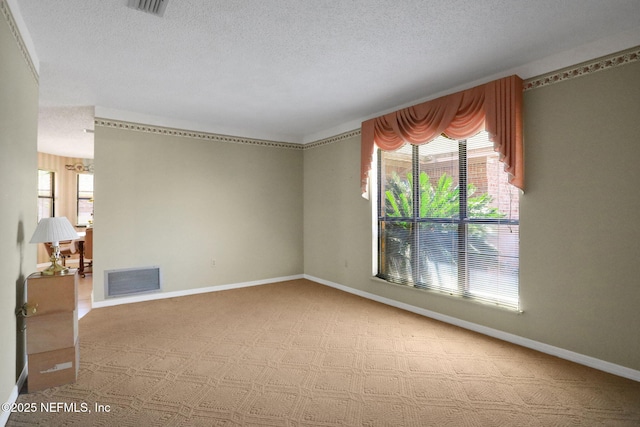 spare room featuring baseboards, visible vents, and a textured ceiling