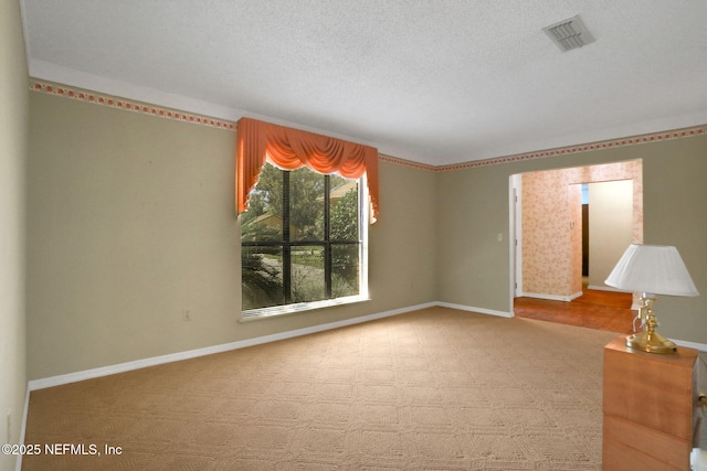 empty room with a textured ceiling, visible vents, and baseboards