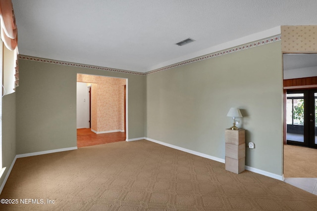 empty room featuring french doors, carpet flooring, visible vents, and baseboards