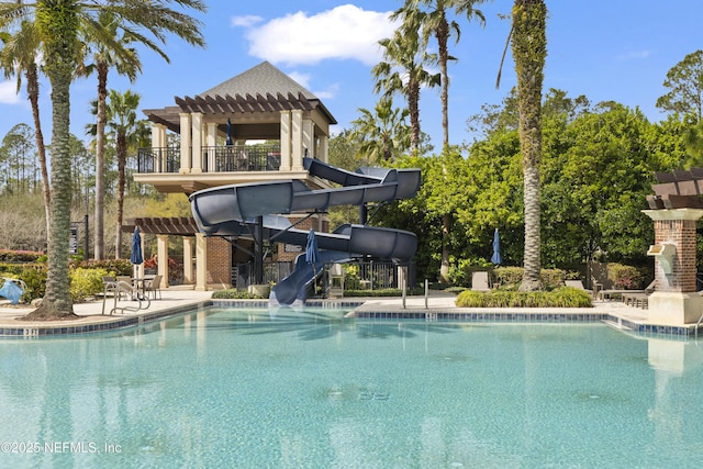 community pool featuring an outdoor fireplace, a pergola, a water slide, and a patio