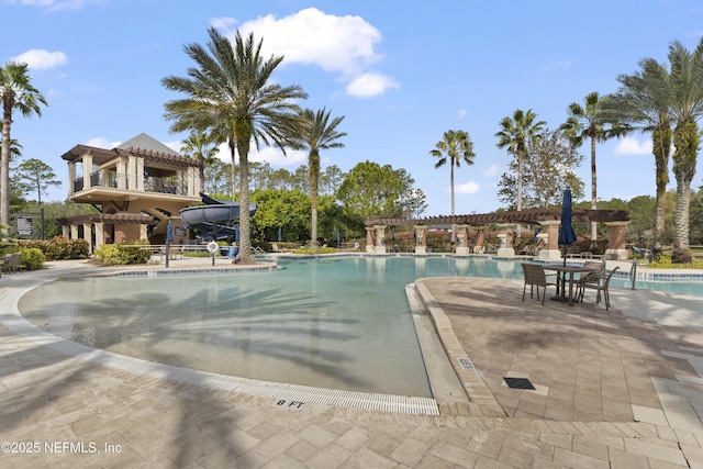 community pool with a water slide, a patio area, and a pergola