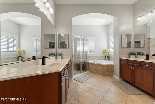 full bath with a shower stall, a sink, a wealth of natural light, and tile patterned floors