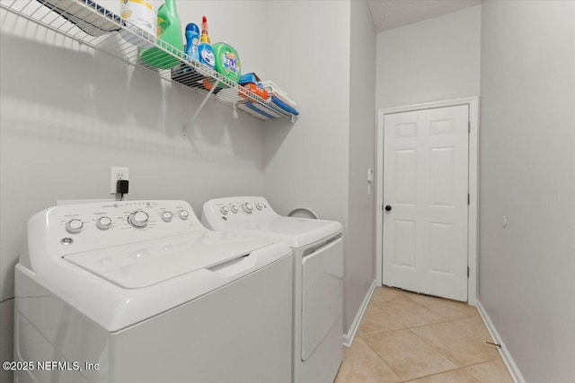 washroom featuring laundry area, light tile patterned floors, baseboards, and washer and clothes dryer