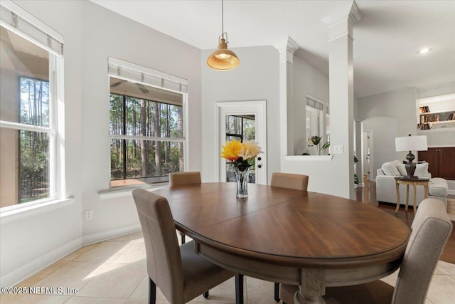 dining area with arched walkways, baseboards, ornate columns, and light tile patterned floors