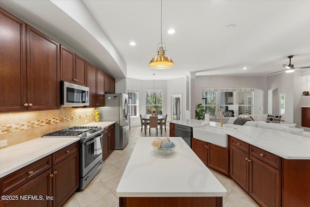 kitchen featuring a spacious island, a sink, open floor plan, appliances with stainless steel finishes, and decorative backsplash