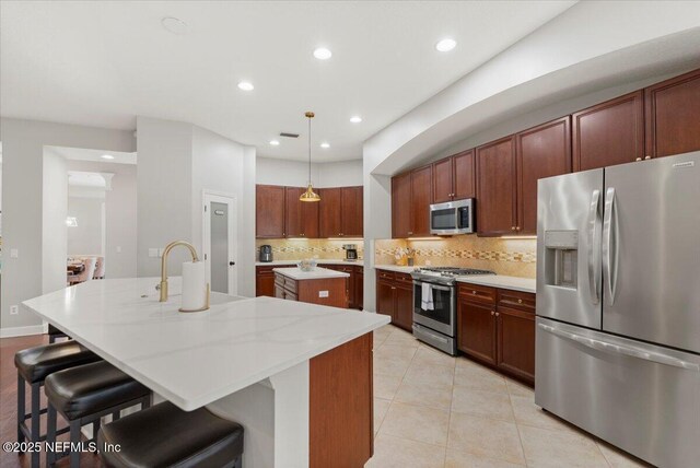 kitchen with light tile patterned floors, a kitchen island with sink, stainless steel appliances, backsplash, and recessed lighting