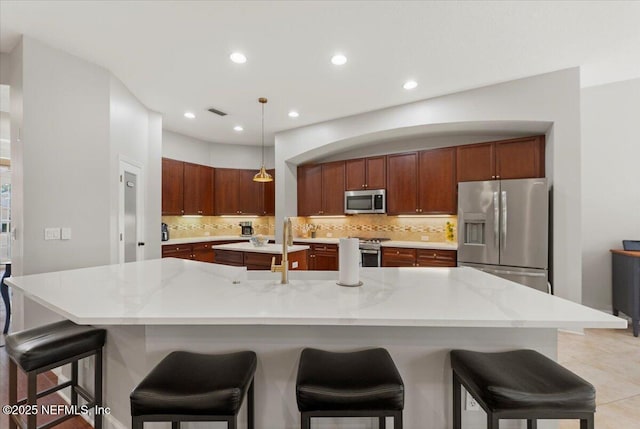 kitchen with stainless steel appliances, visible vents, hanging light fixtures, a large island, and backsplash