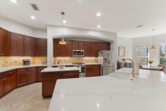 kitchen featuring light tile patterned floors, stainless steel appliances, a sink, visible vents, and a center island