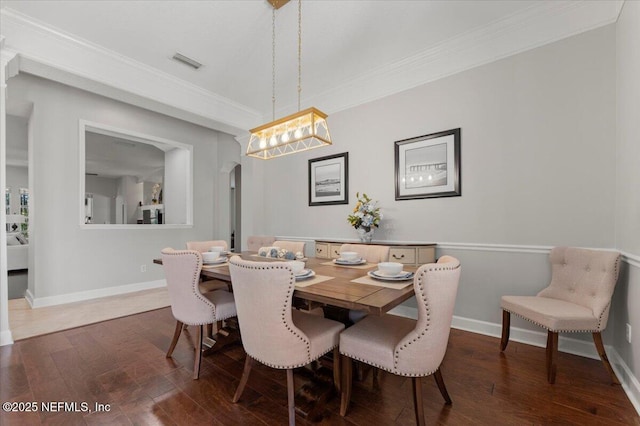 dining space featuring arched walkways, dark wood-type flooring, visible vents, baseboards, and crown molding