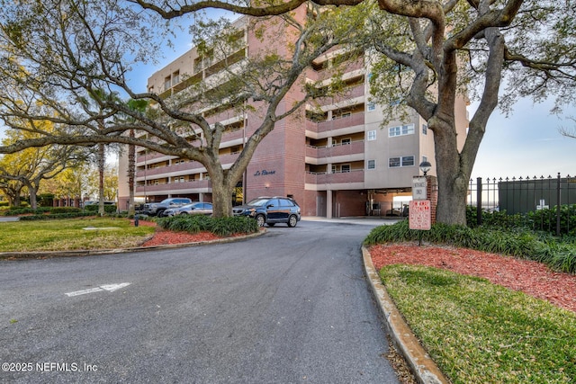 view of building exterior featuring aphalt driveway and fence