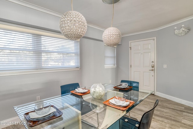dining room featuring an inviting chandelier, crown molding, baseboards, and wood finished floors