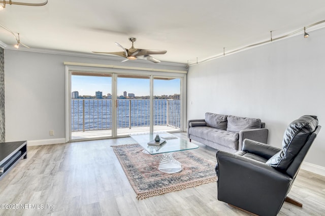 living room featuring a view of city, wood finished floors, crown molding, baseboards, and ceiling fan