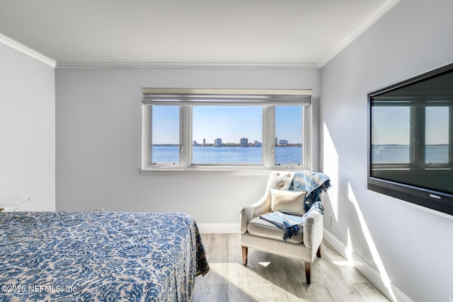 bedroom with wood finished floors, baseboards, a water view, and ornamental molding