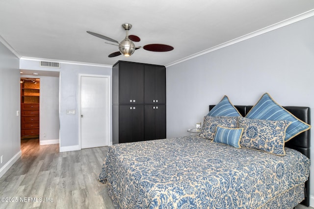 bedroom featuring visible vents, crown molding, baseboards, and wood finished floors