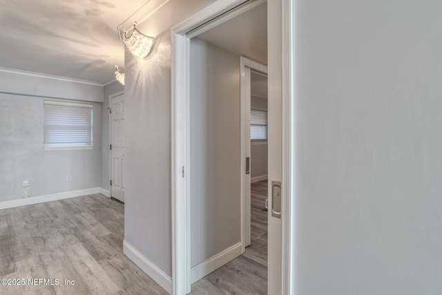 hall featuring baseboards, wood finished floors, and crown molding