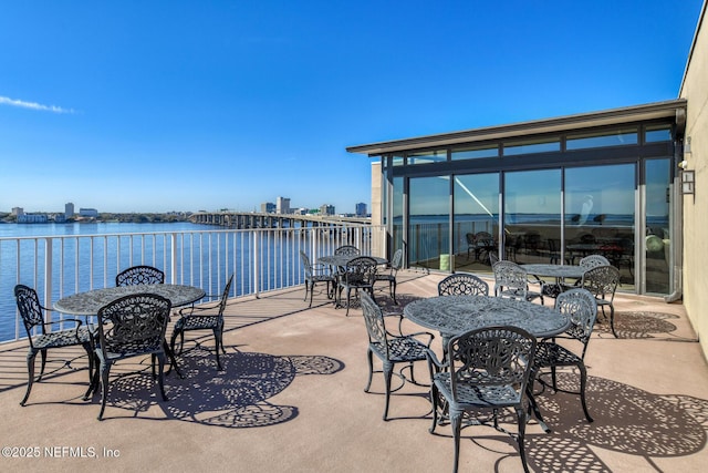view of patio with outdoor dining area, a balcony, and a water view