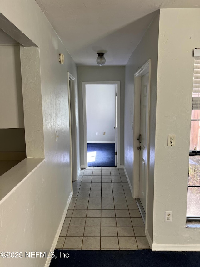 hallway with baseboards and light tile patterned floors