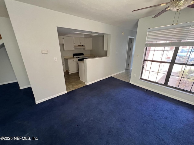 unfurnished living room with carpet floors, tile patterned flooring, ceiling fan, and baseboards