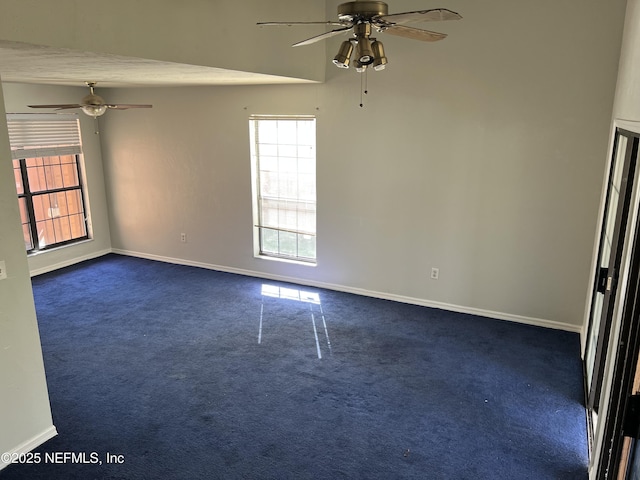 unfurnished room featuring plenty of natural light, dark carpet, and baseboards