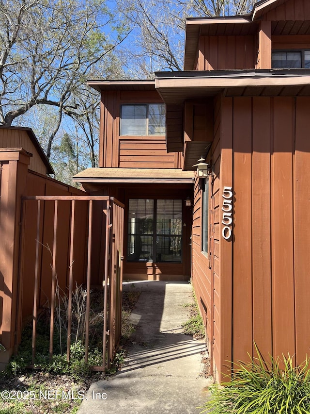 doorway to property featuring fence and board and batten siding