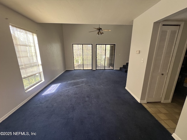 carpeted spare room featuring stairs, ceiling fan, tile patterned flooring, and baseboards