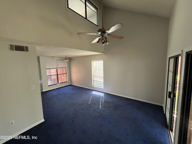 empty room featuring a towering ceiling, baseboards, visible vents, and dark carpet