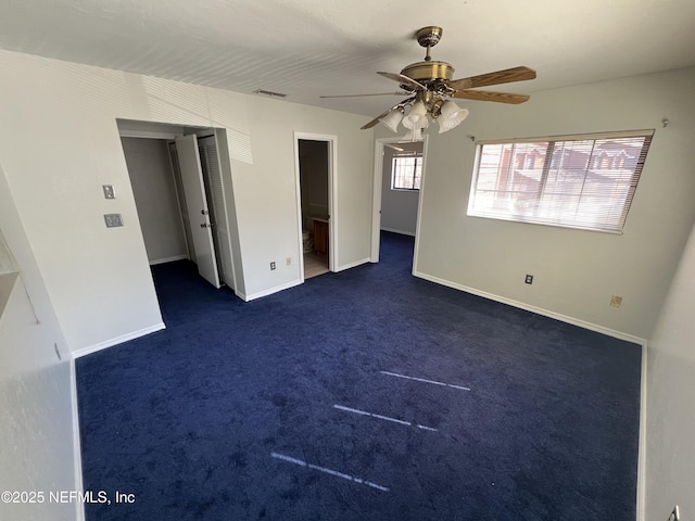 unfurnished bedroom featuring visible vents, dark carpet, baseboards, and ceiling fan