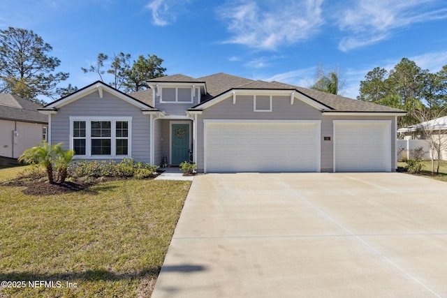 view of front facade with a front lawn, roof with shingles, driveway, and an attached garage