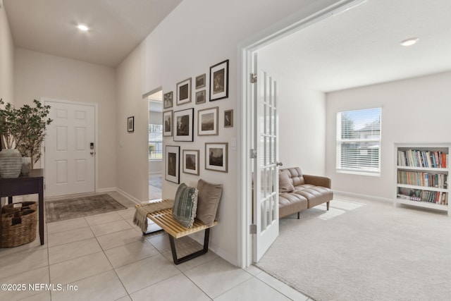 entryway featuring light tile patterned floors, baseboards, and light colored carpet