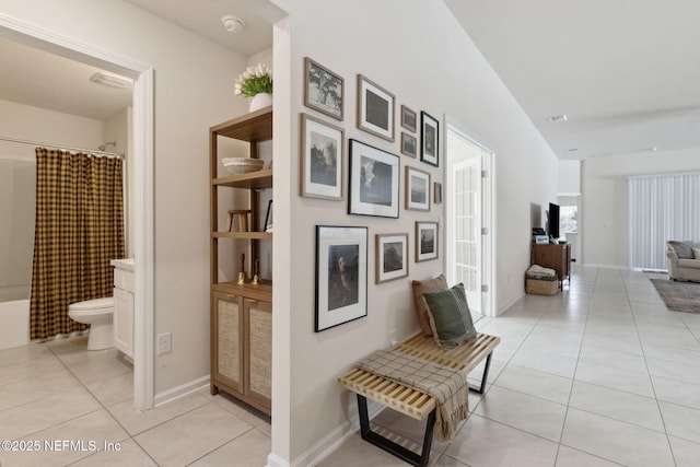 hallway featuring light tile patterned floors and baseboards