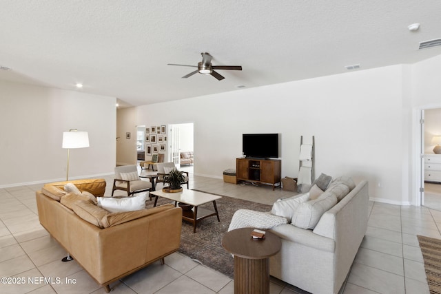 living room featuring a textured ceiling, light tile patterned flooring, visible vents, and a ceiling fan