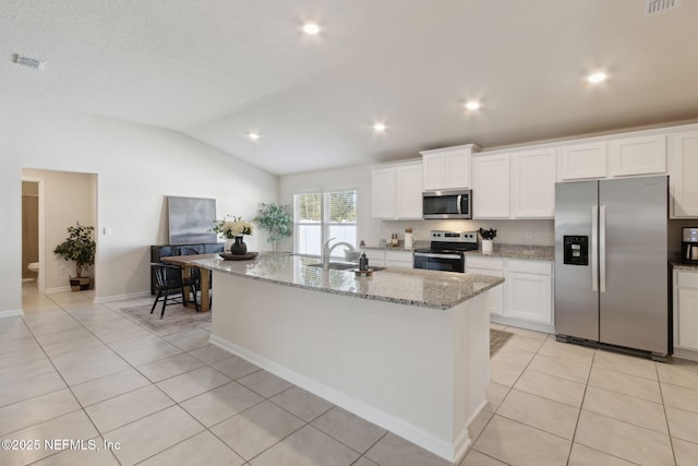 kitchen with light tile patterned floors, white cabinets, vaulted ceiling, stainless steel appliances, and a sink