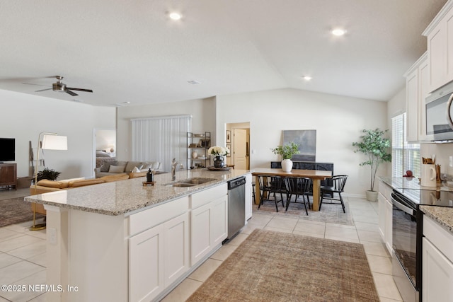 kitchen with light tile patterned flooring, a kitchen island with sink, stainless steel appliances, a sink, and white cabinetry