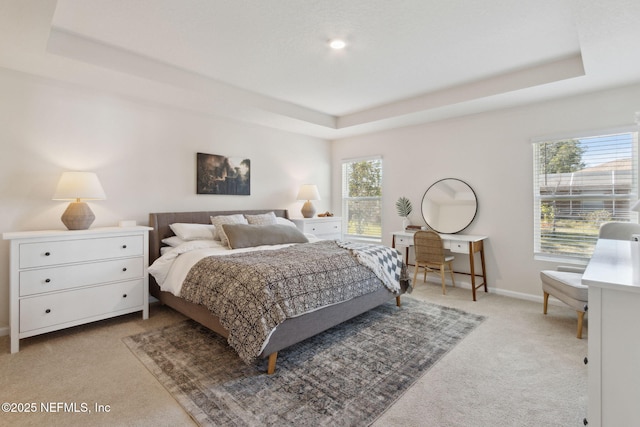 bedroom featuring baseboards, a raised ceiling, and light colored carpet