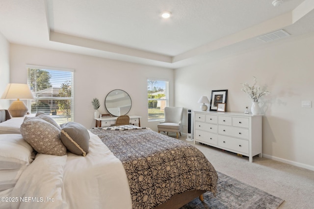 bedroom with baseboards, a raised ceiling, visible vents, and light colored carpet