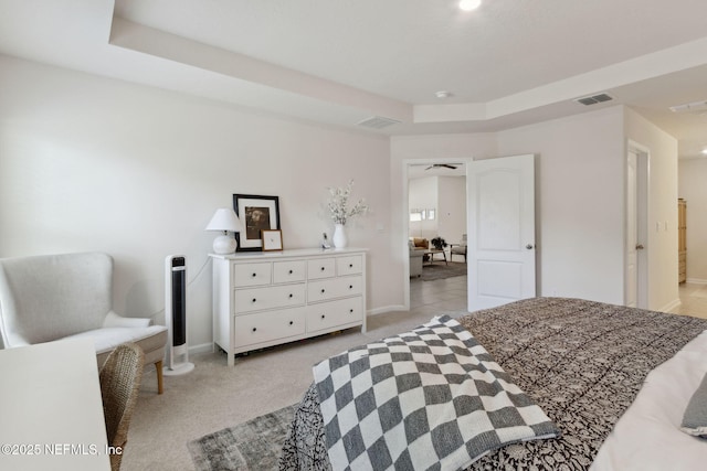 bedroom featuring light carpet, a tray ceiling, visible vents, and baseboards