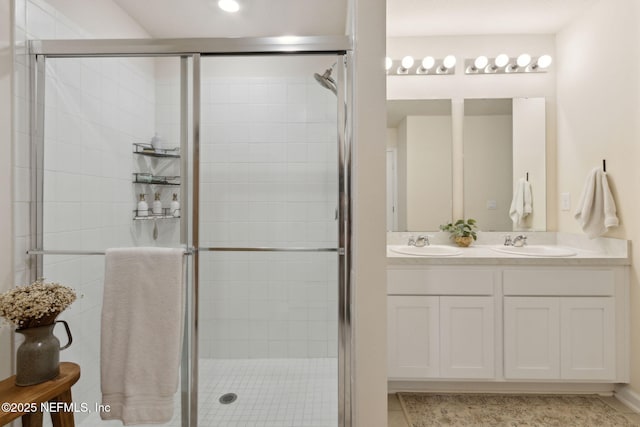 full bathroom featuring double vanity, a stall shower, and a sink