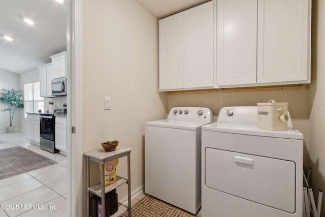 laundry room with cabinet space, light tile patterned floors, baseboards, and washing machine and clothes dryer