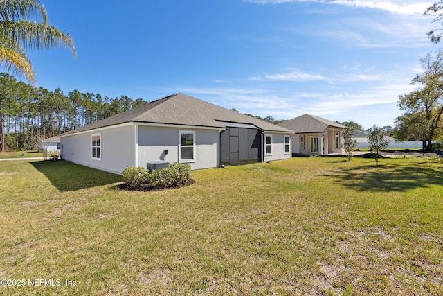 rear view of property with a shingled roof, cooling unit, a yard, and stucco siding