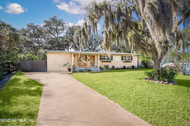 view of front of home with a porch, a front yard, fence, and stucco siding