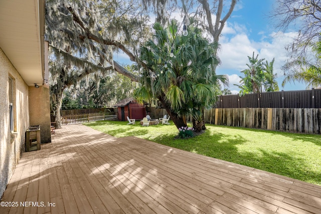 wooden terrace with a lawn, an outdoor structure, and a fenced backyard