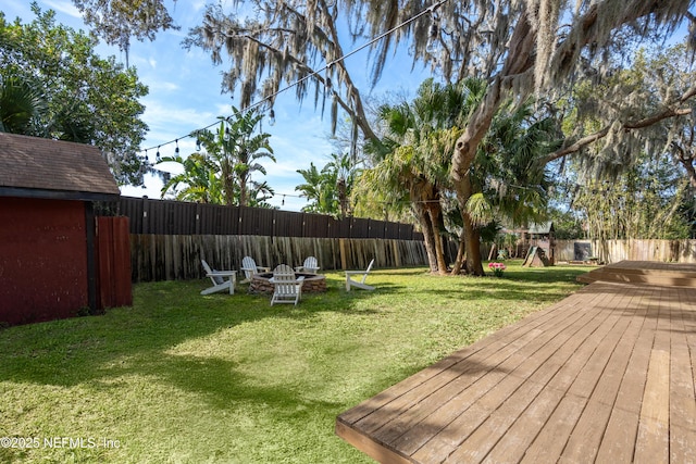 view of yard featuring an outdoor fire pit, a fenced backyard, and a deck