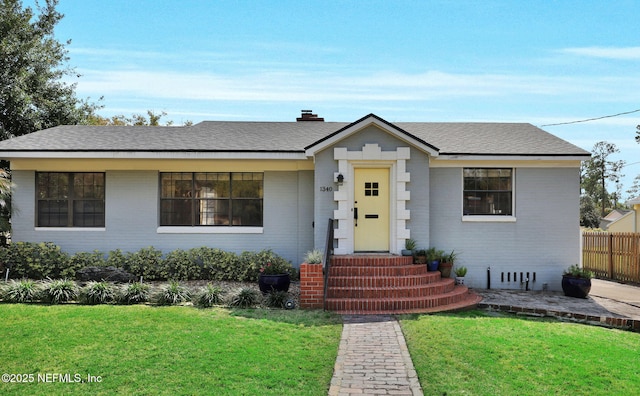 bungalow featuring brick siding, a front lawn, and fence