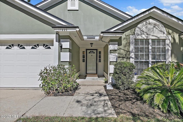 entrance to property with an attached garage and stucco siding