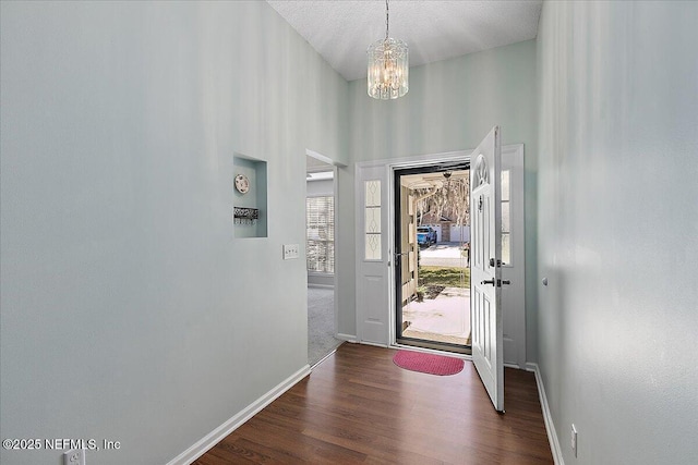 foyer entrance featuring a chandelier, dark wood-style flooring, and baseboards