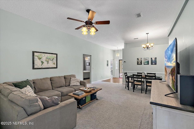 living room with carpet, visible vents, a textured ceiling, baseboards, and ceiling fan with notable chandelier