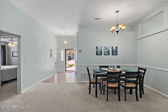 carpeted dining room featuring a textured ceiling, visible vents, and baseboards