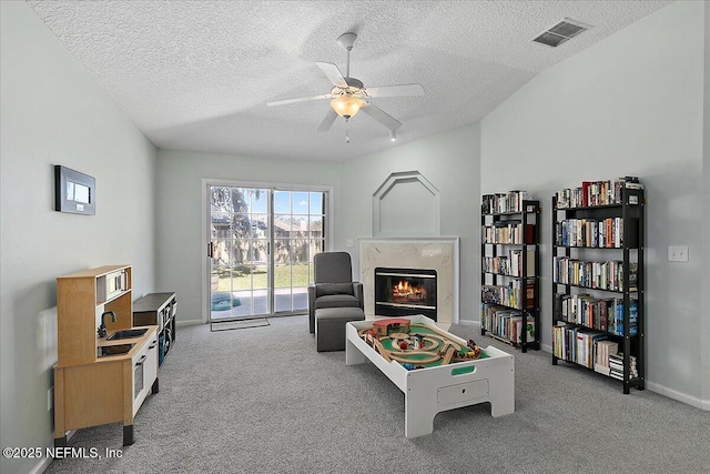 recreation room featuring ceiling fan, a premium fireplace, carpet, and visible vents