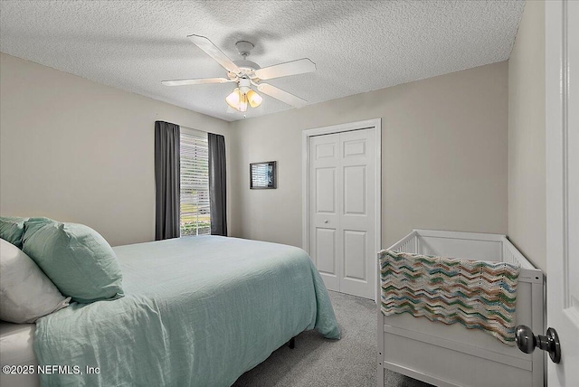 bedroom with a textured ceiling, ceiling fan, a closet, and carpet