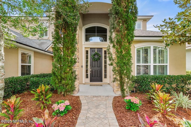 property entrance with roof with shingles and stucco siding